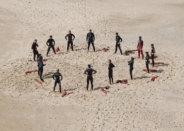 swimmers standing in a circle on the beach