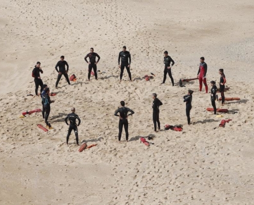 swimmers standing in a circle on the beach